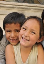 Children smile happily together in a close-up portrait outside project