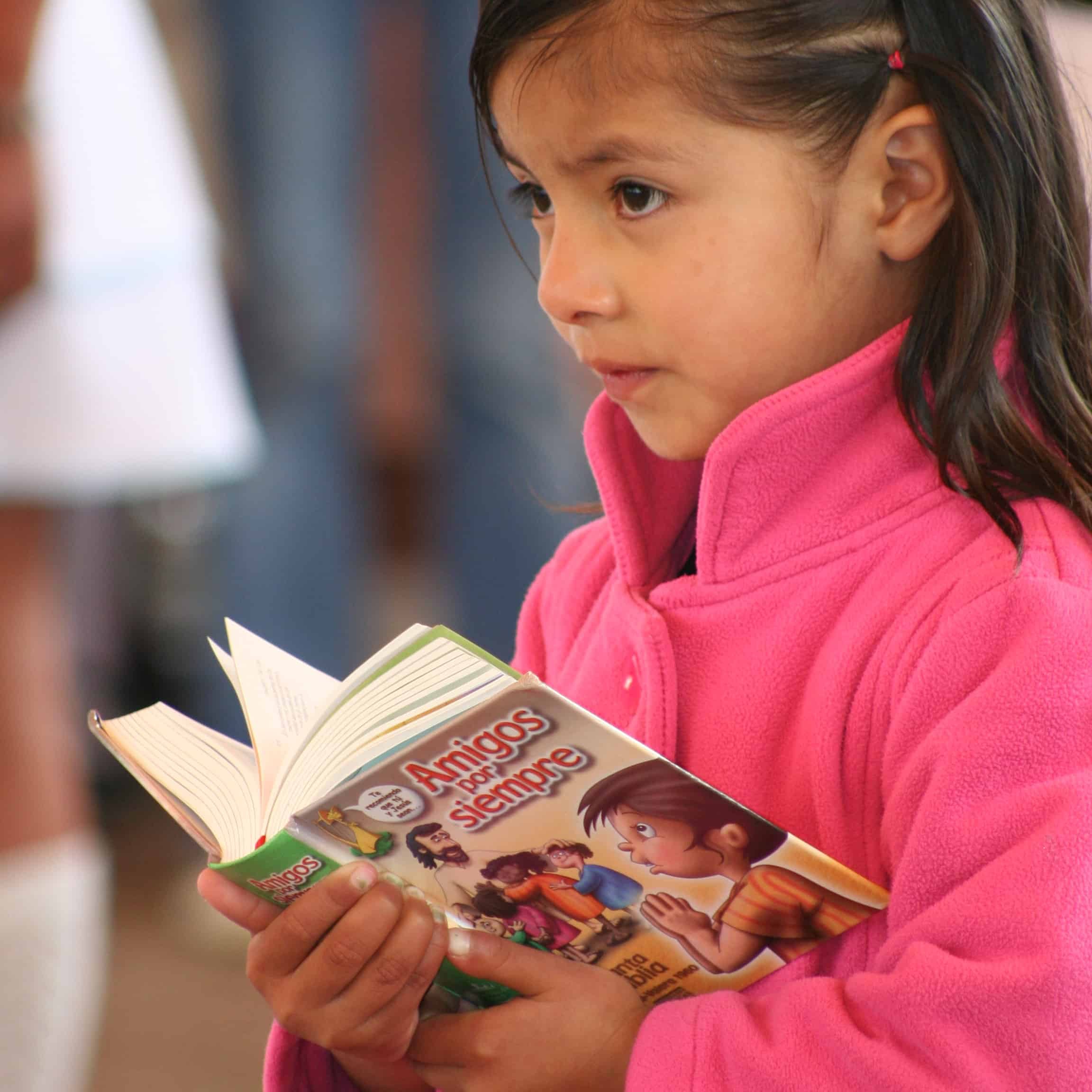A little girl holds a Bible book in her hands