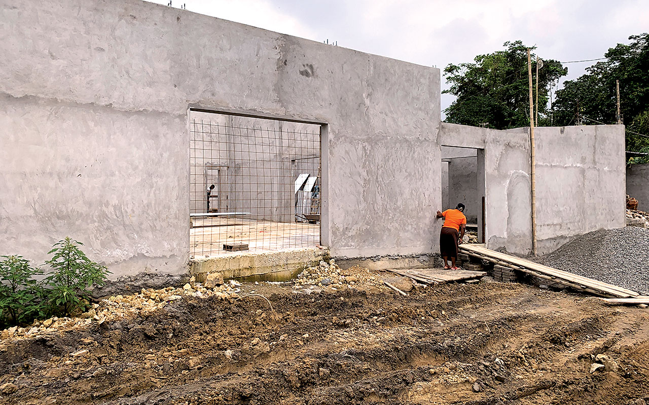 Workers build the front of the structure, including the central door and the door of the patio area.